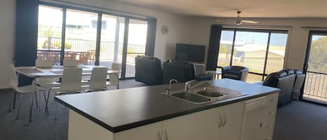 A compact kitchen with a central island, a dining area with chairs, and a seating area with a sofa and chairs.