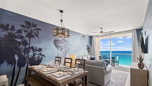 Een eetgedeelte met een tafel voor vier personen, een bank en een balkon met uitzicht op de oceaan.