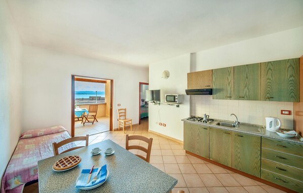 Una cocina compacta con vista al mar, un comedor con una mesa para dos personas y una pequeña sala de estar con televisor y ventana.