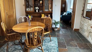 Un coin repas avec une table et des chaises en bois, un meuble avec des portes en verre et une plante en pot.