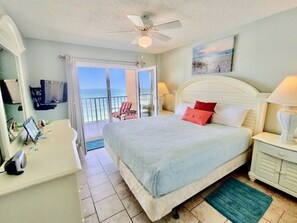 A bedroom with a bed, a nightstand, a TV, a bathroom, and a balcony with a view of the ocean. - Beachfront Condo w/ Gulf Views & Pool (Gulf Shores)