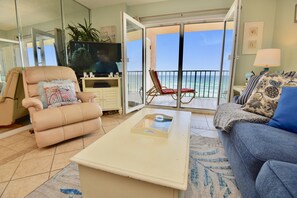 Relax in this stylish living room with a sofa, armchair, and coffee table, opening to a balcony with ocean views.