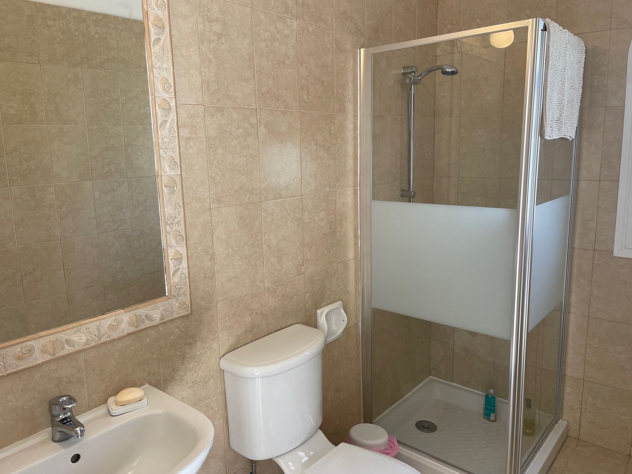 Ein Badezimmer mit Dusche, Toilette, Waschbecken und einem großen Spiegel.