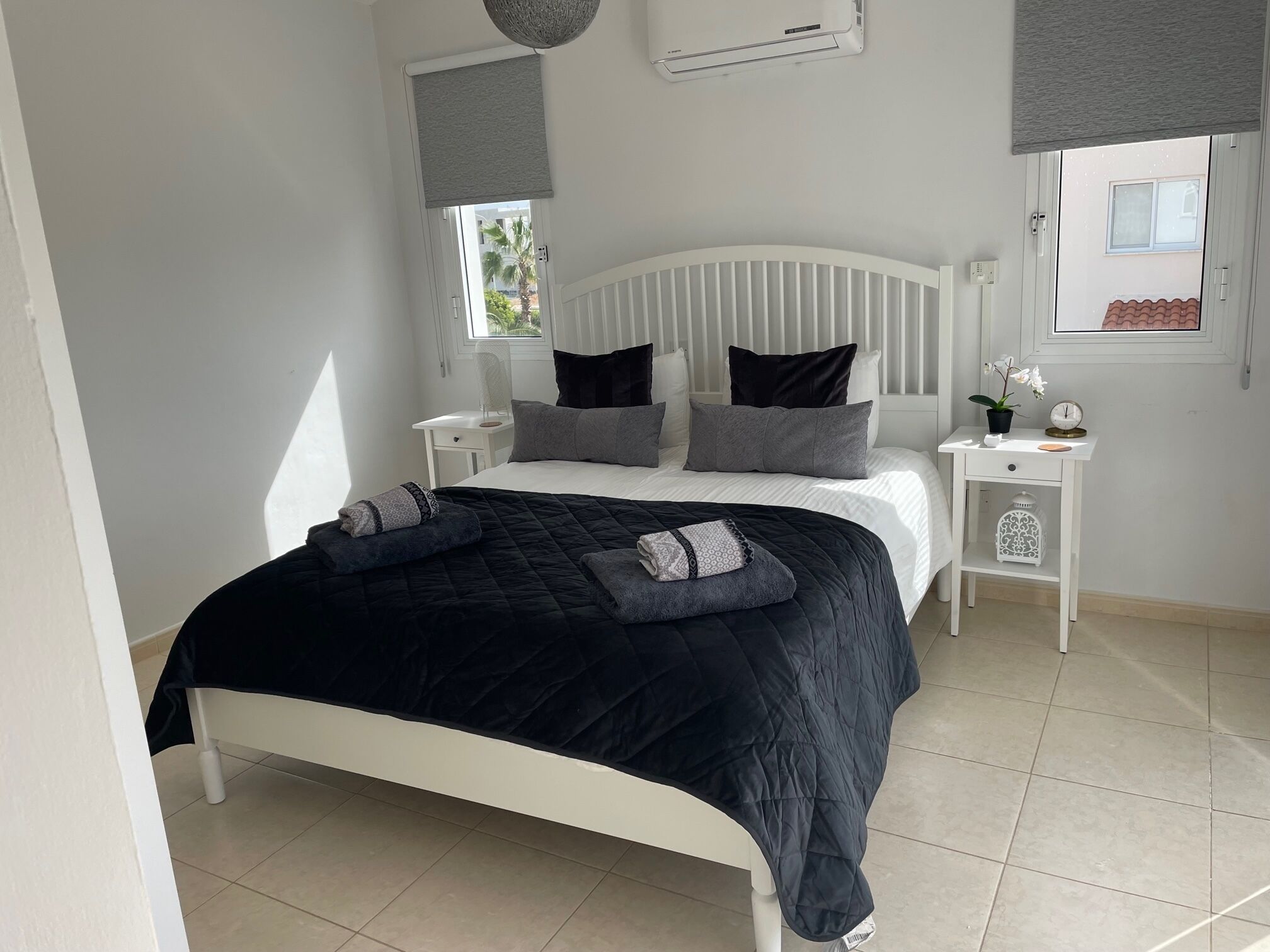 Une chambre à coucher bien rangée, avec un lit, des tables de chevet et une fenêtre.