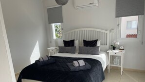 Une chambre à coucher bien rangée, avec un lit, des tables de chevet et une fenêtre.