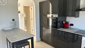 Une cuisine moderne avec des meubles noirs, un four Bosch et une machine à café rouge.