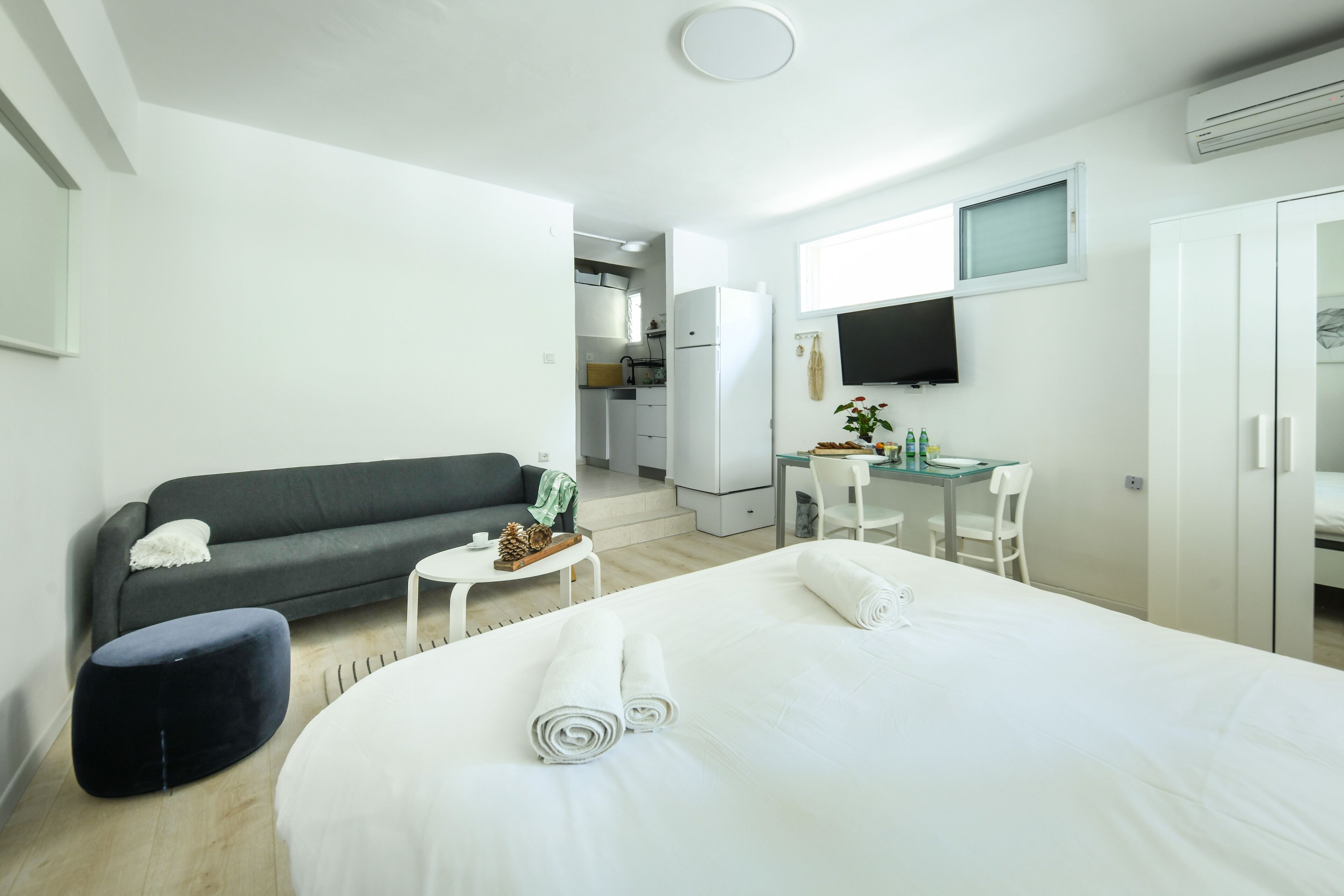 A modern hotel room with a large bed, a sofa, a small table, and a TV.