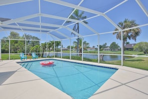 A covered swimming pool with a view of a lake and palm trees. - Tropical Reef - Heated Pool, Newly Renovated, Outdoor Games, 10 Min to AMI (Bradenton)