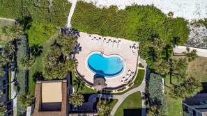 An aerial view of a pool area with a circular pool, surrounding lounge chairs, and palm trees. - Concha 5 in Belleair Beach (Belleair Beach)