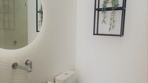 Et badeværelse med en hvid vask, toilet og spejl.