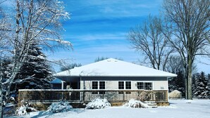 A single-story house with a snow-covered roof and a wooden deck. - Luxurious Getaway - Near Sandbanks and Wineries (Picton)
