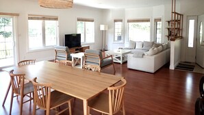 A spacious living area with a wooden dining table, chairs, a sofa, and a television. - Luxurious Getaway - Near Sandbanks and Wineries (Picton)