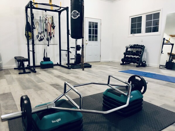 Ein Heimfitnessraum mit Gewichtbank, Squat-Rack und verschiedenen Gewichten.