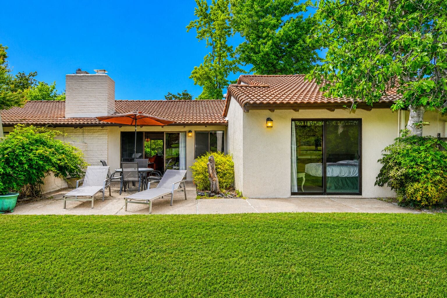 Una casa con patio, mobiliario exterior y un espacio cubierto.