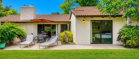 Una casa con patio, mobiliario exterior y un espacio cubierto.