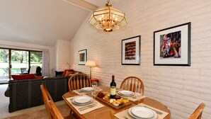 Un comedor con una mesa de madera preparada para cuatro personas, una araña colgante y obras de arte enmarcadas en las paredes.