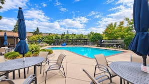 A swimming pool with lounge chairs and umbrellas, surrounded by greenery and a clear sky. - Perfect Wine Country Retreat at Silverado (Napa)