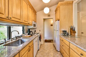 A kitchen with wooden cabinets, a stainless steel sink, a microwave, a stove, and a refrigerator.