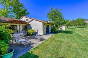 A house with a patio, outdoor furniture, and a well-maintained lawn.
