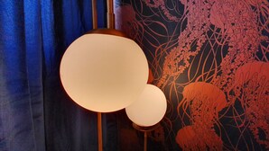 Une pièce dotée d’un grand luminaire rond et d’un mur orné d’un motif abstrait rouge.