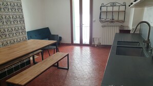 A kitchen with a wooden table and bench, a sink, and a stove. - Charming village house in Provence, French Riviera South of France, 6km from sea (La Valette-du-Var)