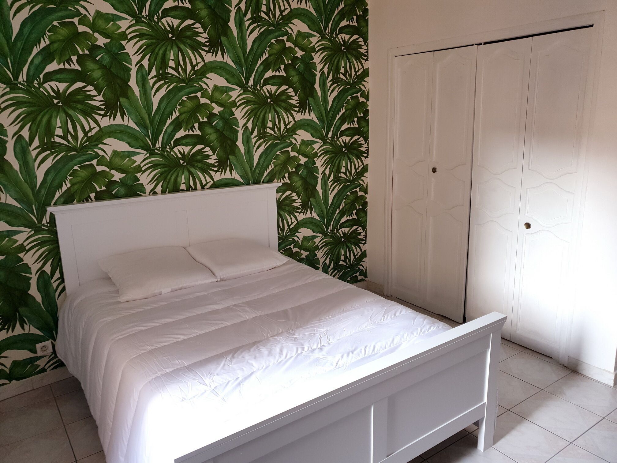 A bedroom with a bed, white headboard, and a door.