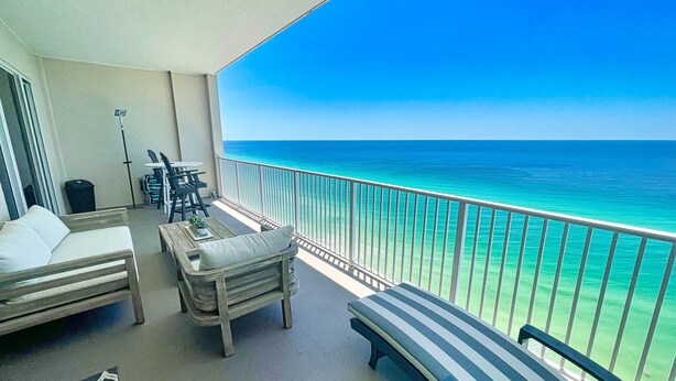 A balcony with a view of the ocean, furnished with a sofa, a bench, and a table. - Exquisite Beach Condo, Comfortable, Luxurious, Beachfront, Free Beach Service (Panama City Beach)