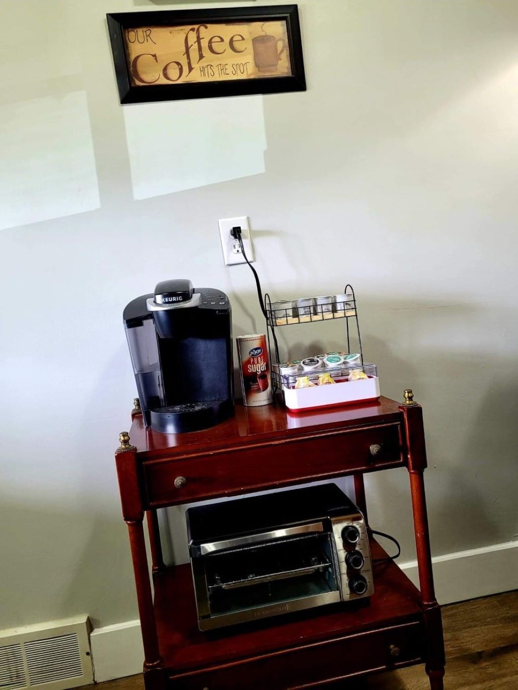A kitchenette with a coffee maker, a toaster, and a coffee mug on a wooden cart.