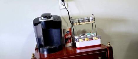 A kitchenette with a coffee maker, a toaster, and a coffee mug on a wooden cart.