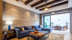 Uma sala de estar moderna com um sofá seccional, uma mesa de centro e uma grande janela com vista para o exterior.