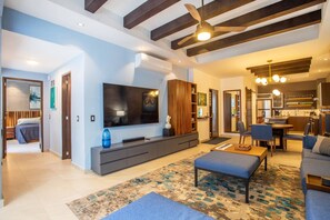 A modern living room with a flat-screen TV, a sofa, a coffee table, and a patterned rug.