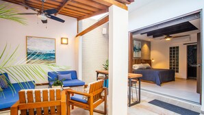 Interior moderno com teto de madeira, um sofá azul, uma cadeira de madeira, uma cama e um espaço de refeições.