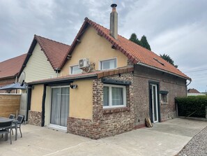 A two-story house with a red-tiled roof, a brick section, and a beige exterior.