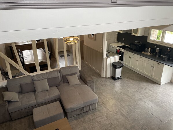 A modern living room with a grey sectional sofa, a small table, and a trash bin.