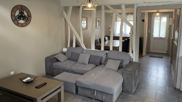 Un salon moderne avec un canapé d’angle, une table basse en bois et une horloge murale.