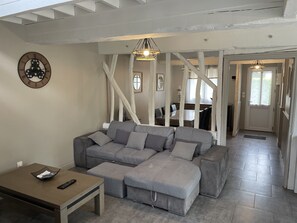 A modern living room with a sectional sofa, a wooden coffee table, and a wall clock.
