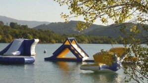 Un llac amb estructures flotants, presumiblement per activitats aquàtiques, envoltat de turons i arbres.