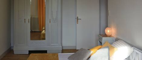 A bedroom with a bed, a wardrobe, and a bedside lamp.