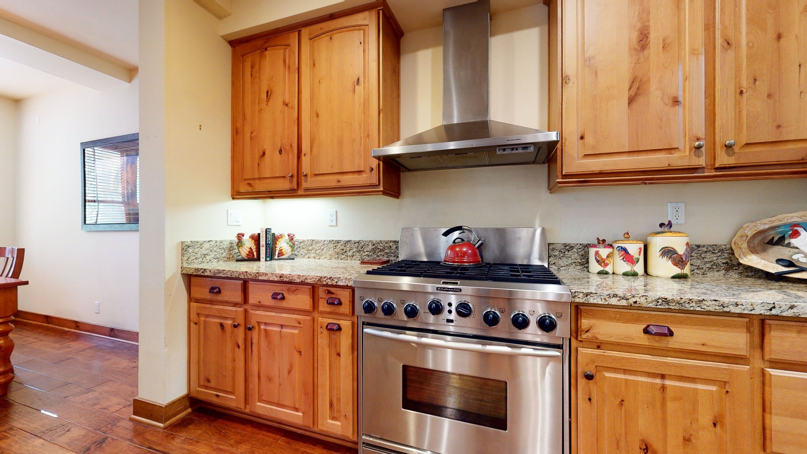 A kitchen with wooden cabinets, a stainless steel stove, and granite countertops.