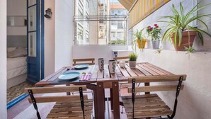 A wooden table with chairs, a window, and potted plants on a balcony. - Apartment (Barcelona)