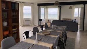A dining area with a table set for six, a bookshelf, and a view of the sea. - House (Criel-sur-Mer)