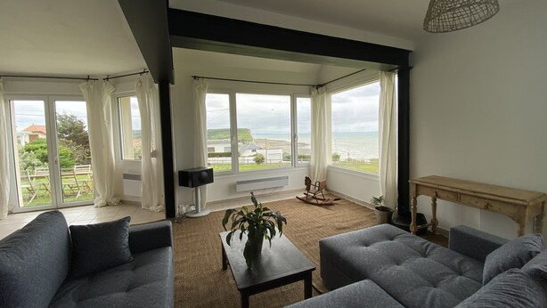 A living room with a grey sofa, a coffee table with a plant, and a view of the sea through large windows. - House (Criel-sur-Mer)