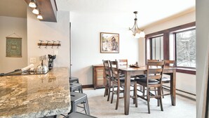 A dining area with a granite countertop, wooden chairs, and a chandelier. - Park Place Peak 10 Condo: Walk To Lift, Main Street (Breckenridge)