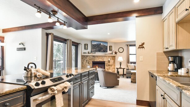 A modern kitchen with granite countertops, stainless steel appliances, and wooden beams. - Park Place Peak 10 Condo: Walk To Lift, Main Street (Breckenridge)