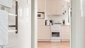 A modern kitchen with white cabinets, a microwave, and a stove. - Cosy Coastal Retreat in Stieglitz with Water Views (Stieglitz)