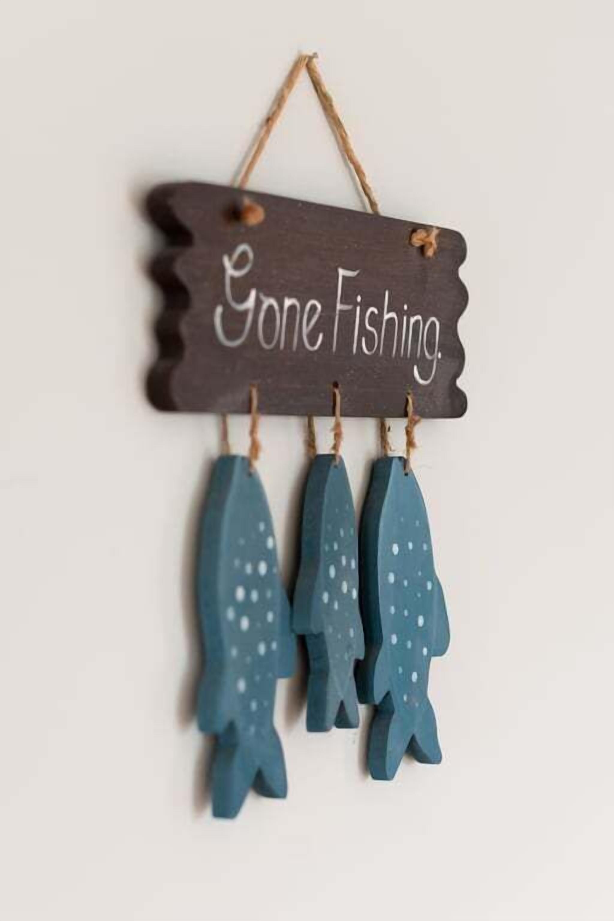 A wooden sign with the text "Gone Fishing." and three hanging fish figures.