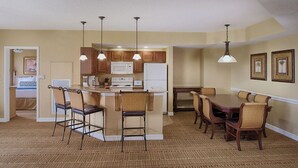 A modern kitchen with a central island, bar stools, and a dining table with chairs. - 2 bedroom, resort amenities, Disney convenient location!  (Lake Buena Vista)