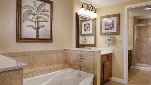 A bathroom with a bathtub, vanity, and two framed floral paintings. - 2 bedroom, resort amenities, Disney convenient location!  (Lake Buena Vista)