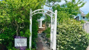 A pathway leading to a white gate with a sign for a real estate agency. - 13 Collins Street, Unit B, Dewey Beach, Delaware (Dewey Beach)