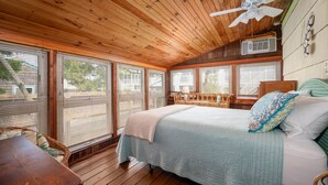 A wooden-paneled bedroom with a bed, a ceiling fan, and large windows. - 13 Collins Street, Unit B, Dewey Beach, Delaware (Dewey Beach)